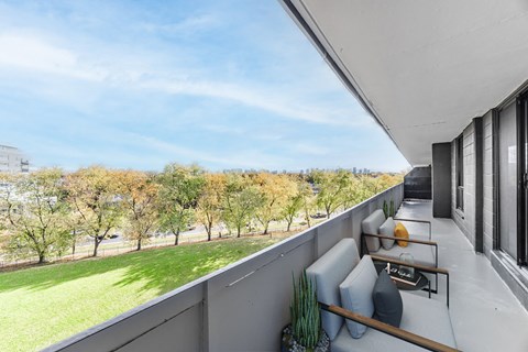 A balcony with a couch and a table with a vase on it.
