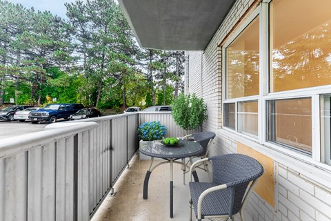 A balcony with a table and chairs overlooking a parking lot.