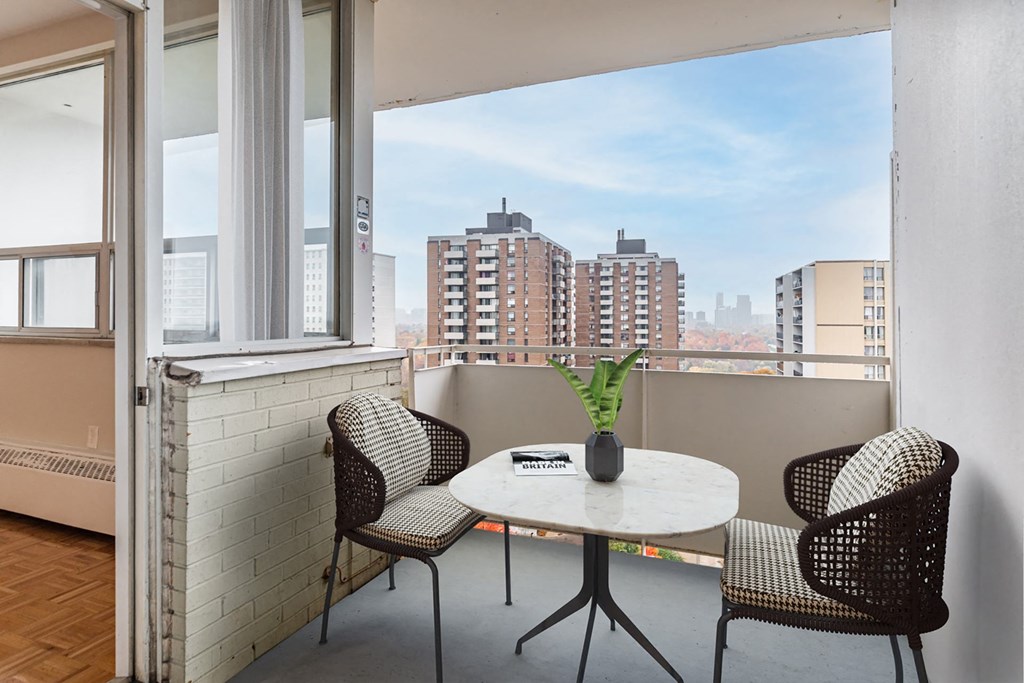 A balcony with a table and chairs overlooking a cityscape.