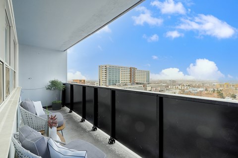 A balcony with chairs and a table overlooking a cityscape.