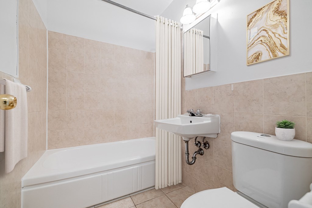 A bathroom with a white tub, sink, and toilet.