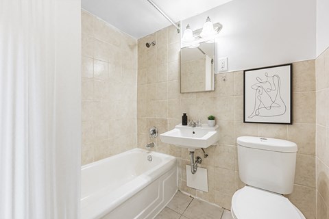 A bathroom with a white tub, sink, and toilet.