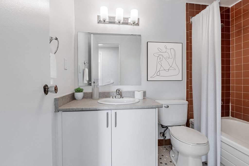 A white bathroom with a toilet, sink, and mirror.