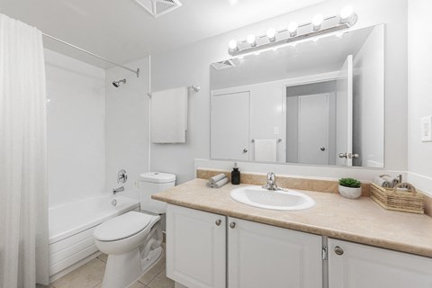 A white bathroom with a toilet, sink, and mirror.