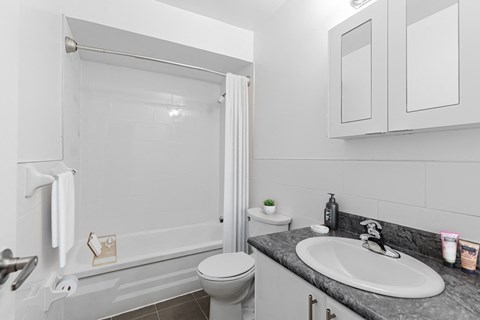 A white bathroom with a toilet, sink, and shower.