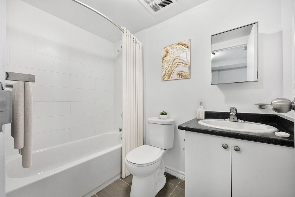 A white bathroom with a toilet, sink, and shower.
