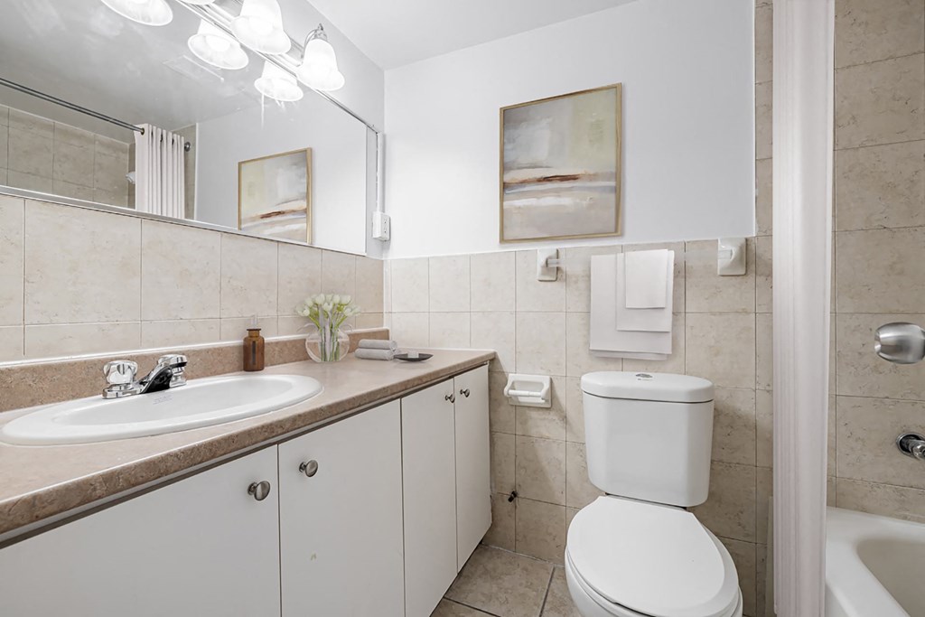 A white toilet is in a bathroom with a sink and mirror.