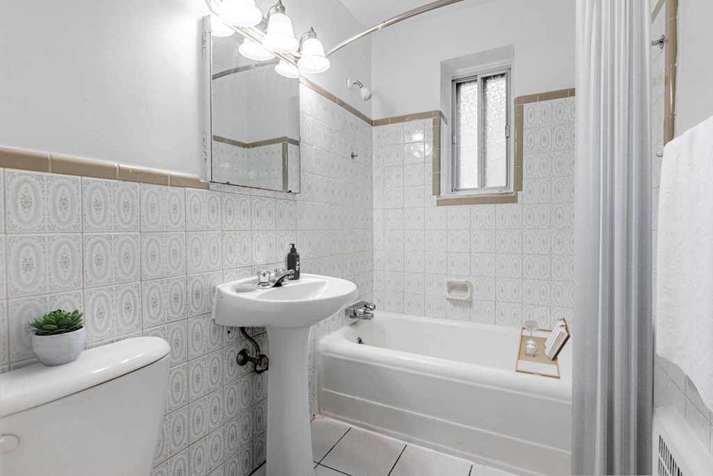A white bathroom with a tub, sink, and mirror.