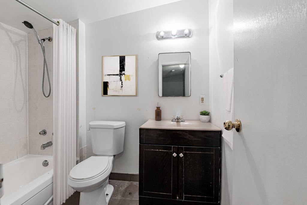 A white toilet sits next to a white bathtub in a bathroom.