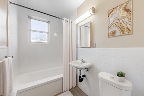 A bathroom with a white toilet, sink, and bathtub.