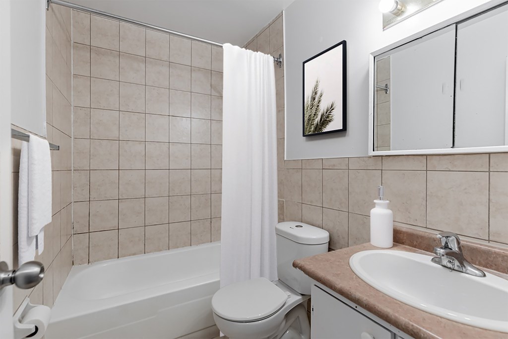 A white toilet sits next to a white bathtub in a bathroom.