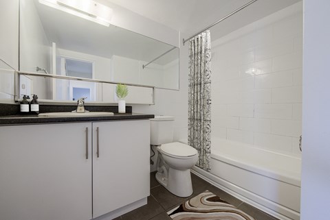 A white toilet sits in a bathroom next to a bathtub.