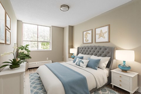 A bedroom with a large bed, a blue blanket, and a white nightstand with a blue lamp.