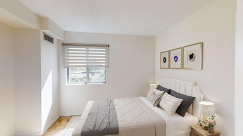 A bedroom with a bed, nightstand, and pictures on the wall.