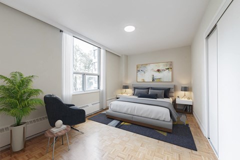 A bedroom with a large bed, a chair, and a potted plant.