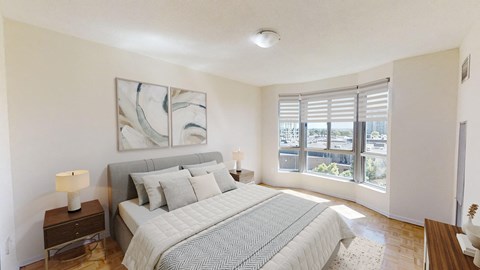 A bedroom with a large bed, a nightstand with a lamp, and a painting on the wall.