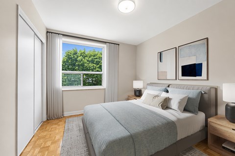 A bedroom with a large bed and a view of trees outside the window.