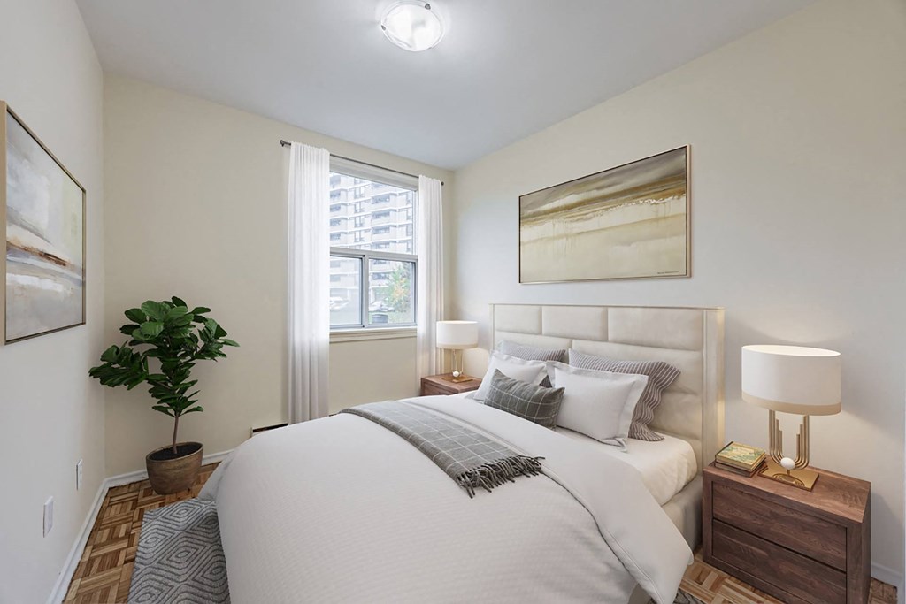 A well-lit bedroom with a large bed, a nightstand with a lamp, and a potted plant.