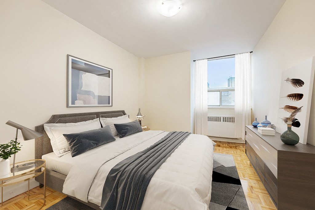 A bedroom with a large bed and a window with white curtains.
