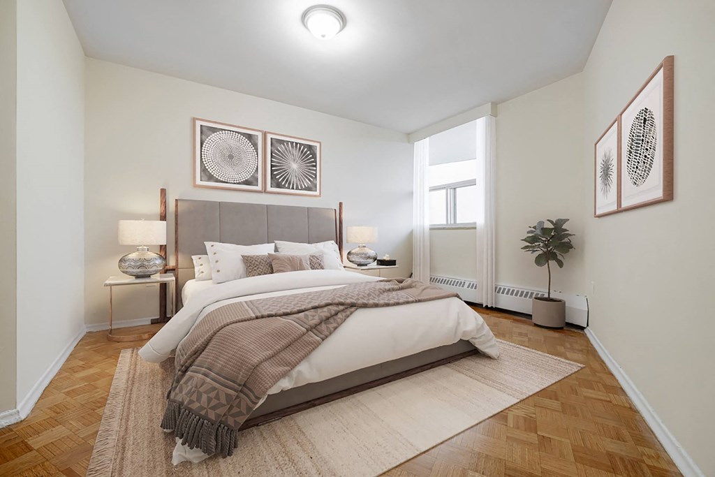 A bedroom with a large bed and a rug on the floor.