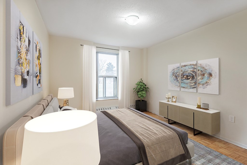 A bedroom with a bed, nightstand, and a large window.