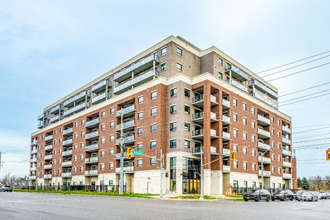 A large red brick apartment building with a parking lot in front.