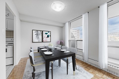 A dining room with a table set for two and a view of a building outside the window.