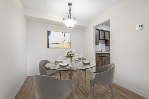A dining room with a table set for two and a painting on the wall.