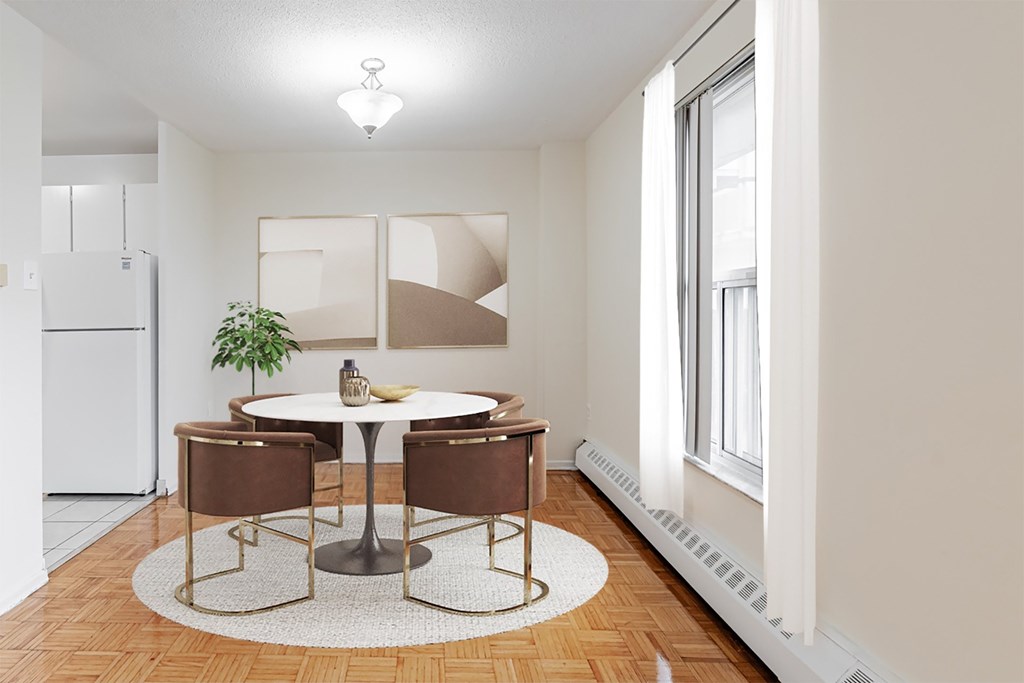 A dining room with a white fridge, brown chairs, and a white table.
