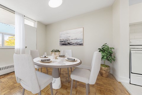 A dining room with a table set for two and a potted plant.