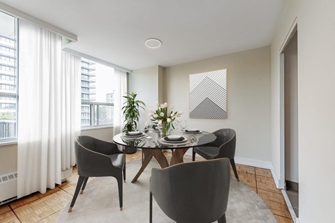 A dining room with a table set for two and a view of a building outside the window.