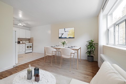 A white dining table with four chairs is in the middle of a room.