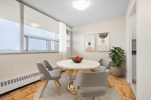 A dining room with a round table and grey chairs.