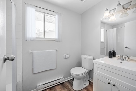 A white bathroom with a toilet, sink, and mirror.