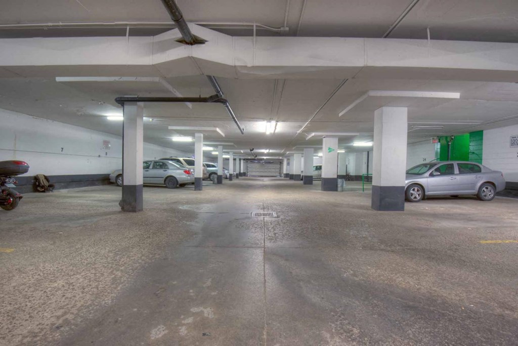 A parking garage with a concrete floor and white pillars.