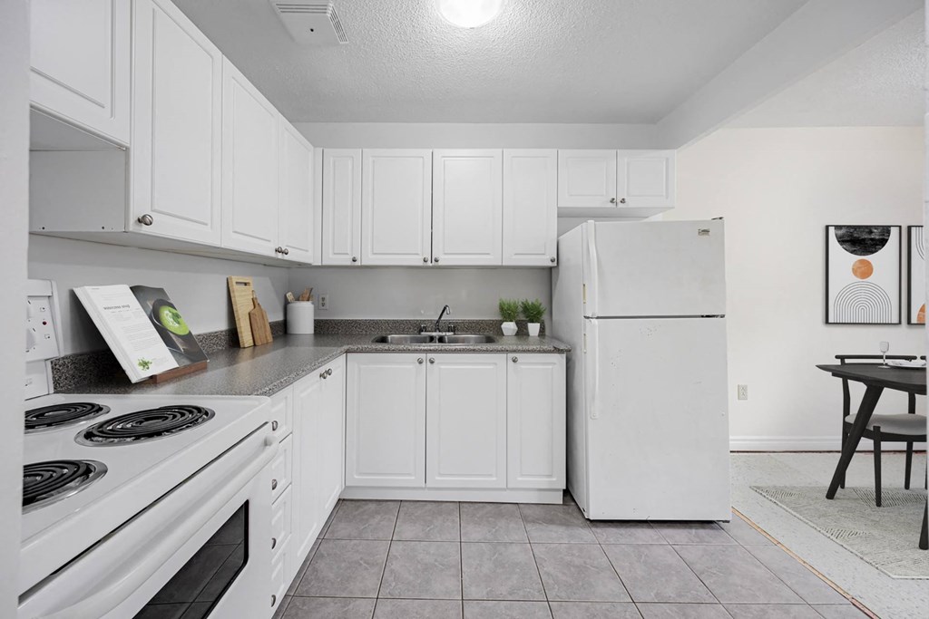 A kitchen with white cabinets and a white refrigerator.
