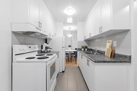 A white kitchen with a stove, oven, and sink.