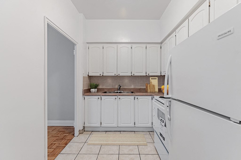 A kitchen with white cabinets and a white fridge.