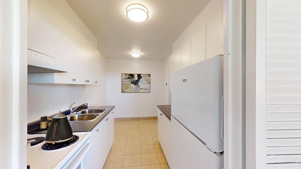 A kitchen with white cabinets and a white fridge.