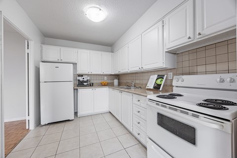 A white kitchen with a stove and refrigerator.