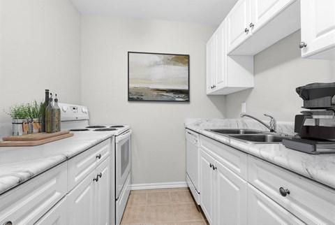 A kitchen with white cabinets and a marble countertop.