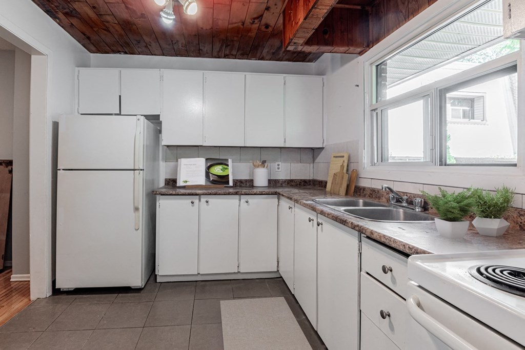 A kitchen with white cabinets and a wooden ceiling.