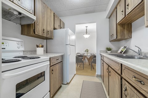 A kitchen with white appliances and wooden cabinets.