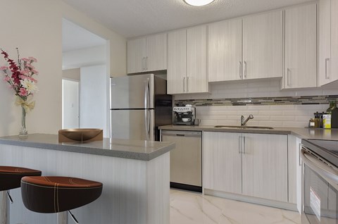 A kitchen with a refrigerator, stove, and cabinets.