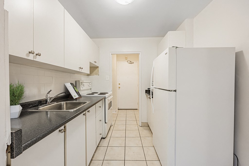 A kitchen with white cabinets and a black counter top.