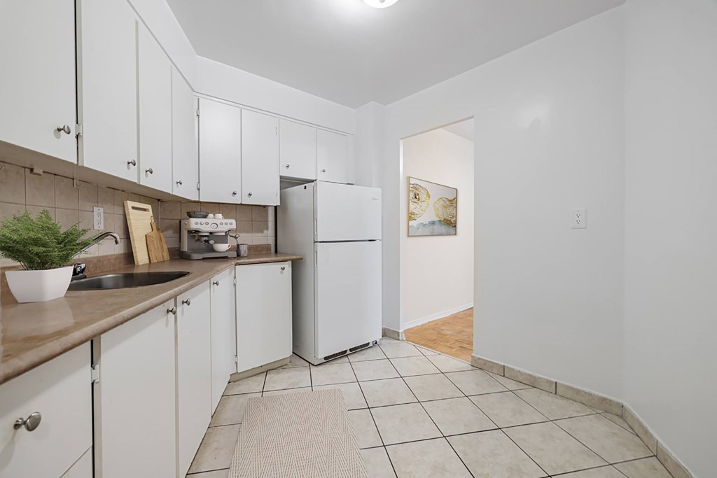 A kitchen with white cabinets and a white fridge.