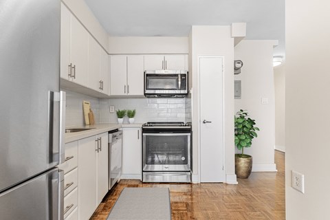 A kitchen with white cabinets and a stainless steel refrigerator.