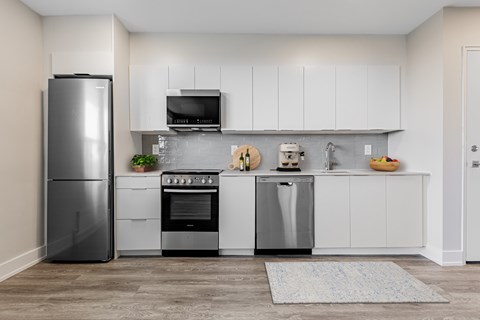 A modern kitchen with a refrigerator, oven, and sink.
