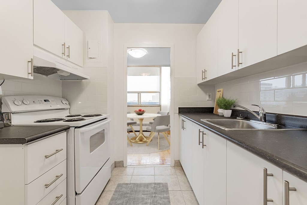 A kitchen with white cabinets and black countertops.
