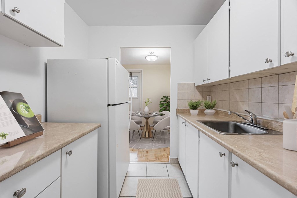 A kitchen with white cabinets and a refrigerator.